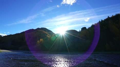 Slowmotion-panning-shot-of-sunflares-over-the-mountains-while-water-is-streaming