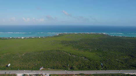 Luftaufnahme-Einer-Erweiterung-Mit-Grüner-Und-Unberührter-Vegetation-Mit-Einer-Straße-Und-Im-Hintergrund-Der-Horizont-Mit-Dem-Blauen-Meer
