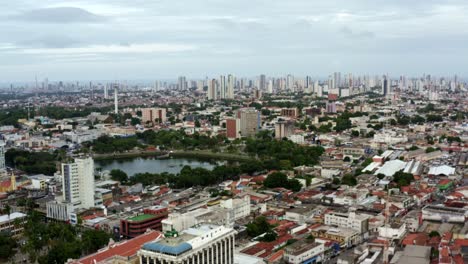 Truck-left-aerial-shot-of-the-old-downtown-of-the-tropical-coastal-capital-city-of-Joao-Pessoa,-Paraiba,-Brazil-with-old-skyscrapers,-historic-homes,-churches-the-famous-lagoon-during-golden-hour
