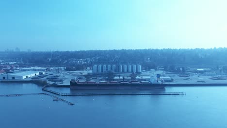 Frachtschiff-Lädt-Rohes-Getreide,-Drohnenüberflug,-Klarer,-Ruhiger-Tag,-Silos-Werden-Auf-Schiff-Verladen