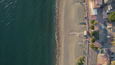 Static-overhead-aerial-shot-over-a-beach-with-waves-and-some-holiday-homes