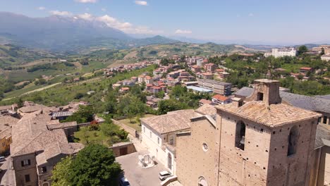 Wide-angle-drone-shot-orbiting-an-old-church-with-a-beautiful-vista-of-mountains-in-the-distance-and-the-village-of-Chieti-in-the-region-of-Abruzzo-in-Italy