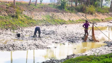 Ein-Paar-Bangladeschischer-Fischer,-Die-Bei-Ebbe-Fische-In-Schlammbecken-Fangen