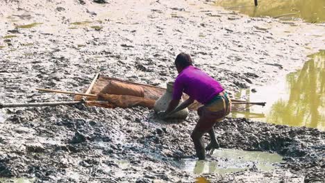 Ein-Bangladeschischer-Fischer-Fängt-Bei-Ebbe-Fische-In-Schlammtümpeln-Und-Legt-Sie-In-Einen-Weidenkorb