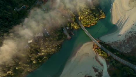 Top-down-aerial-view-of-the-Pacific-Coast-Highway-in-California-crossing-a-river-in-the-early-morning-glow