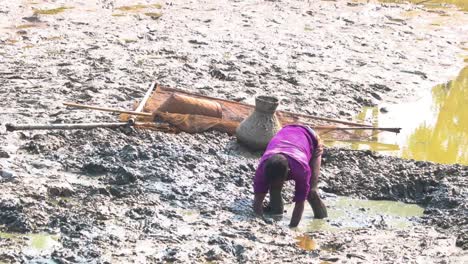Bangladeshi-Fisherman-Digging-Out-Large-Clumps-Of-Mud-From-Small-Pool-In-Low-Tide-To-Find-Fish