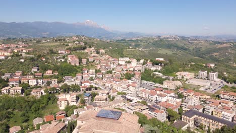 Wide-angle-drone-shot-of-a-remote-village-in-Italy-panning-up-towards-a-mountain-range