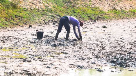 Male-Seen-Digging-Out-Mud-Clay-From-Low-Tide-Riverbank-Searching-For-Fish-In-Bangladesh