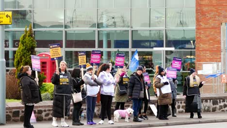 Underfunded-NHS-workers-at-Whiston-hospital-in-St-Helens,-Merseyside-protest-on-the-picket-line-with-banners-and-flags-demanding-fair-pay