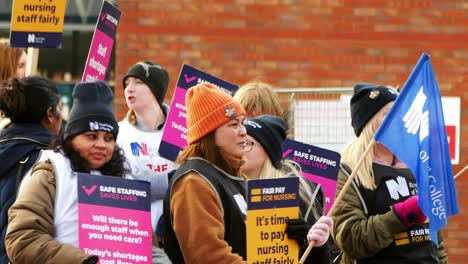 Unterfinanziertes-Und-überarbeitetes-NHS-Personal-Im-Whiston-Hospital-In-St.-Helens,-Merseyside,-Streit-Auf-Der-Streikpostenlinie-Mit-Transparenten-Und-Fahnen,-Die-Faire-Lohnbedingungen-Fordern