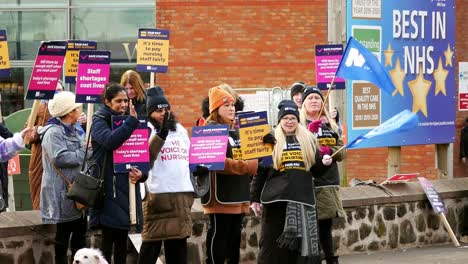 Underfunded-and-overworked-NHS-staff-at-Whiston-hospital-in-St-Helens,-Merseyside-protest-on-the-picket-line-with-banners-and-flags-demanding-fair-pay