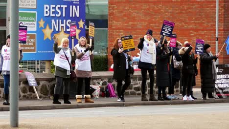 Überlastete-NHS-Mitarbeiter-Protestieren-Vor-Dem-Krankenhaus-In-St.-Helens-An-Der-Streikpostenkette-Mit-Transparenten-Und-Fahnen,-Die-Eine-Faire-Bezahlung-Fordern