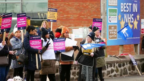 Überlastete-NHS-Mitarbeiter-Im-Whiston-Hospital-In-St.-Helens,-Merseyside,-Protestieren-An-Der-Streikpostenlinie-Mit-Transparenten-Und-Fahnen,-Die-Eine-Faire-Bezahlung-Fordern