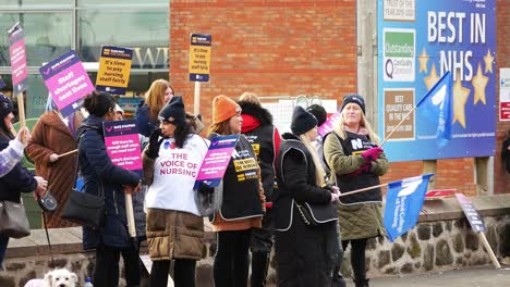 Overworked-NHS-staff-at-Whiston-hospital-in-St-Helens,-protest-on-the-picket-line-with-banners-and-flags-demanding-fair-pay