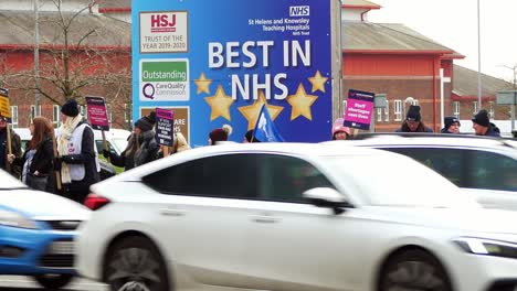 Overworked-NHS-staff-strike-at-Whiston-hospital-in-St-Helens-protest-on-the-picket-line-with-banners-and-flags-demanding-fair-pay