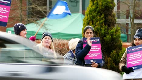 Überlastete-NHS-Arbeiter-Im-Krankenhaus-In-Merseyside-Protestieren-An-Der-Streikpostenkette-Mit-Transparenten-Und-Fahnen,-Die-Eine-Faire-Bezahlung-Fordern