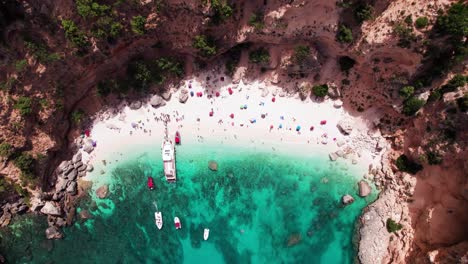 Aerial-top-down-of-tropical-beach-with-turquoise-sea-on-rocky-coast-bay,-Sardinia