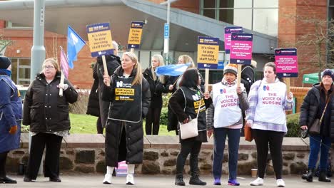 Underfunded-and-overworked-NHS-workers-at-Whiston-hospital-in-St-Helens-protesting-on-the-picket-line-with-banners-and-flags-demanding-fair-pay
