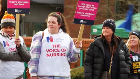 Unterfinanzierte-Und-überarbeitete-NHS-Arbeiter-Protestieren-An-Der-Streikpostenlinie-Mit-Transparenten-Und-Fahnen,-Die-Eine-Faire-Bezahlung-Fordern