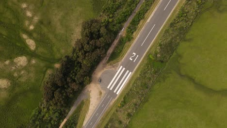 Aerial-top-down-shot-Emergency-runway-on-rural-road-in-Uruguay-during-sunny-day-surrounded-by-green-forest
