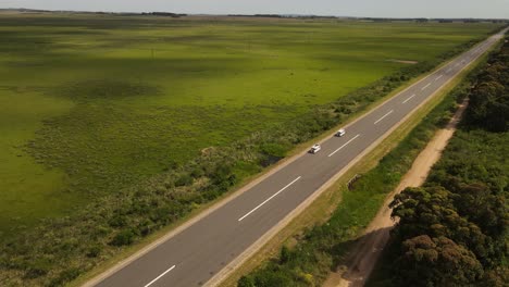 Two-identical-vans-driving-along-rural-road-in-Uruguay