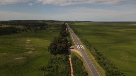 Aerial-backwards-shot-of-emergency-airstrip-on-rural-road-in-Uruguay-during-sunny-day