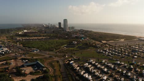 South-Padre-Island,-Texas-at-golden-hour-aerial-4k-drone-push-in-over-street-and-coastline