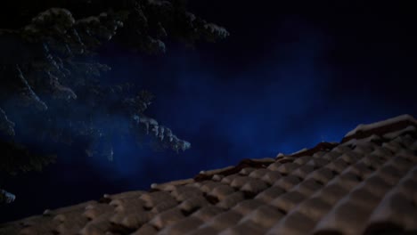 House-roof-covered-in-snow-near-spruce-tree-forest-with-smoke-of-chimney-at-night-sky-background