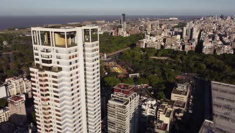 Aerial-orbit-shot-of-residential-block-tower-in-suburb-area-of-Buenos-Aires---Skyline-in-background-during-sunny-day