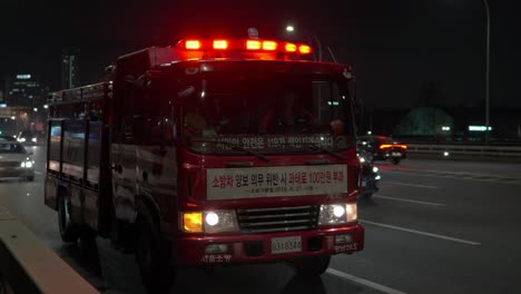 Firetruck-or-Fire-Engine-With-Red-Flashing-Emergency-Lights-Driving-on-Busy-Seoul-Street-at-Night-in-slow-motion