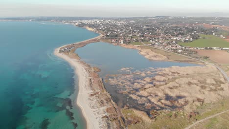 Aerial-drone-shot-wetland-next-sea-coastline-village-in-distance