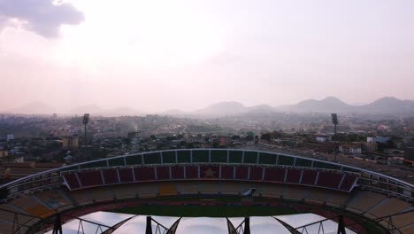 Aerial-view-over-the-Amadou-Ahidjo-stadium,-sunset-in-Yaounde,-Cameroon---reverse,-drone-shot