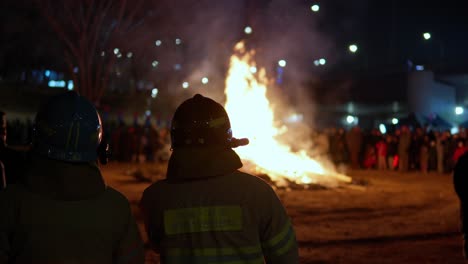 Yangjae-District-Firemen-Standing-Near-Daljip-Burning-Fire-at-Night-Seoul-at-Jeongwol-Daeboreum-First-Full-Moon-Festival-in-Gangnam,-Seoul-on-February-5,-2023---slow-motion