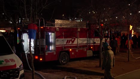 Bomberos-Que-Conectan-La-Manguera-Contra-Incendios-Para-Suministrar-Agua-Al-Camión-De-Bomberos-Por-La-Noche-En-Seúl