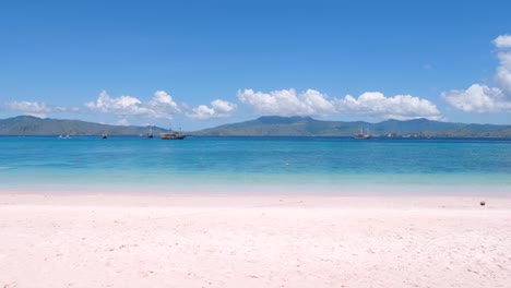 Idyllischer-Blick-Auf-Das-Türkisfarbene-Meer,-Ausflugsboote-Und-Die-Tropische-Insel-Vom-Rosafarbenen-Strand-Auf-Der-Insel-Komodo-In-Flores,-Indonesien
