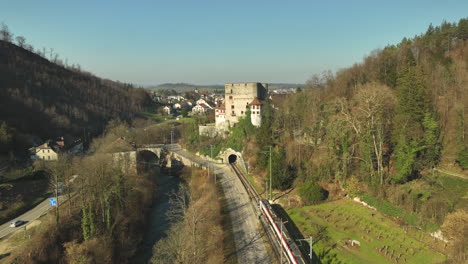 Beautiful-historical-Schloss-Angenstein-builded-on-a-hill-while-a-regional-train-is-driving-towards-the-tunnel-on-a-clear-autumn-day