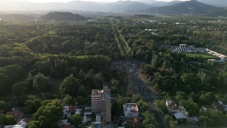 Aerial-Drone-Fly-Above-Mendoza-Town-Argentina-Valley-Below-Andean-Cordillera-Landscape,-Street,-Traffic-Circle-and-Treetops,-Green-Area