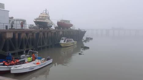 Port-of-Bissau-with-four-small-speedboats-in-the-water-and-two-boats-on-top-of-the-water-access-floor-on-a-foggy-morning