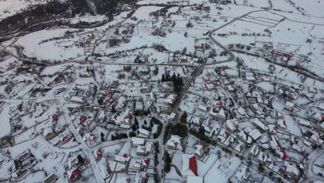 Touristic-village-of-Voskopoja-in-winter-with-traditional-houses-covered-by-snow,-aerial-view-in-Albania