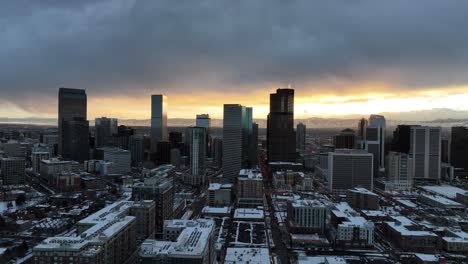 Aerial-view-of-downtown-Denver,-Colorado-covered-in-a-blanket-of-snow-at-sunset