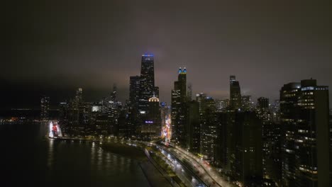 Beleuchtete-Wolkenkratzer-Und-Verkehr-In-Streeterville,-Nebliger-Abend-In-Chicago,-USA-–-Rückzug,-Drohnenaufnahme