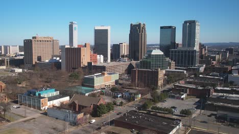 Beautiful-aerial-view-of-downtown-cityscape-of-Birmingham,-Alabama-approaching-skyscrapers-and-parking-in-front-of-blue-skylines
