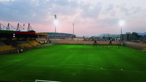 Aerial-view-of-a-soccer-team-practice-at-the-Amadou-Ahidjo-stadium,-sunset-in-Yaounde,-Cameroon