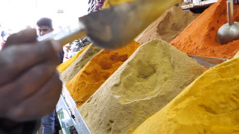 Moroccan-man-picking-up-powdered-spices-with-a-small-shovel-to-sell-from-his-street-stall