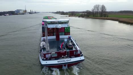 Luftaufnahme-Des-Hecks-Des-Mondlicht-Binnenmotorfrachters,-Der-Entlang-Der-Beneden-Merwede-Fährt-Und-Intermodale-Container-Transportiert