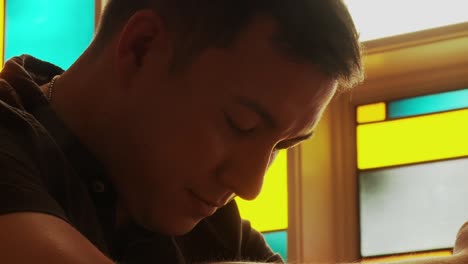 Closeup-of-a-young-ethnic-male-praying-with-his-head-bowed-low-inside-a-church-sanctuary