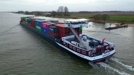 Aerial-Tracking-Shot-Off-Stern-Moonlight-Inland-Motor-Freighter-Sailing-Along-Beneden-Merwede-Carrying-Intermodal-Containers