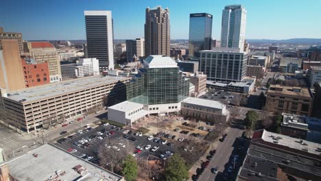 Beautiful-aerial-view-of-downtown-cityscape-of-Birmingham,-Alabama-orbiting-courthouses-and-skyscrapers-in-front-of-a-blue-skyline