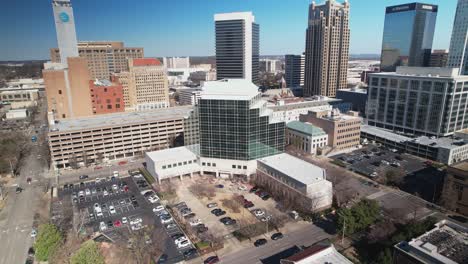 Beautiful-aerial-view-of-downtown-cityscape-of-Birmingham,-Alabama-approaching-courthouse-and-skyscrapers-in-front-of-a-blue-skyline