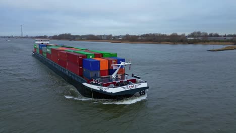 Aerial-Tracking-Shot-Along-Starboard-Side-Of-Moonlight-Inland-Motor-Freighter-Sailing-Along-Beneden-Merwede-Carrying-Intermodal-Containers-On-Overcast-Day